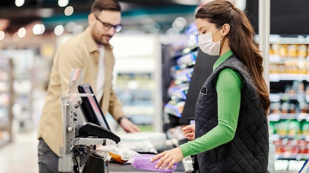 A cashier charges for groceries and goods at supermarket during covid 19