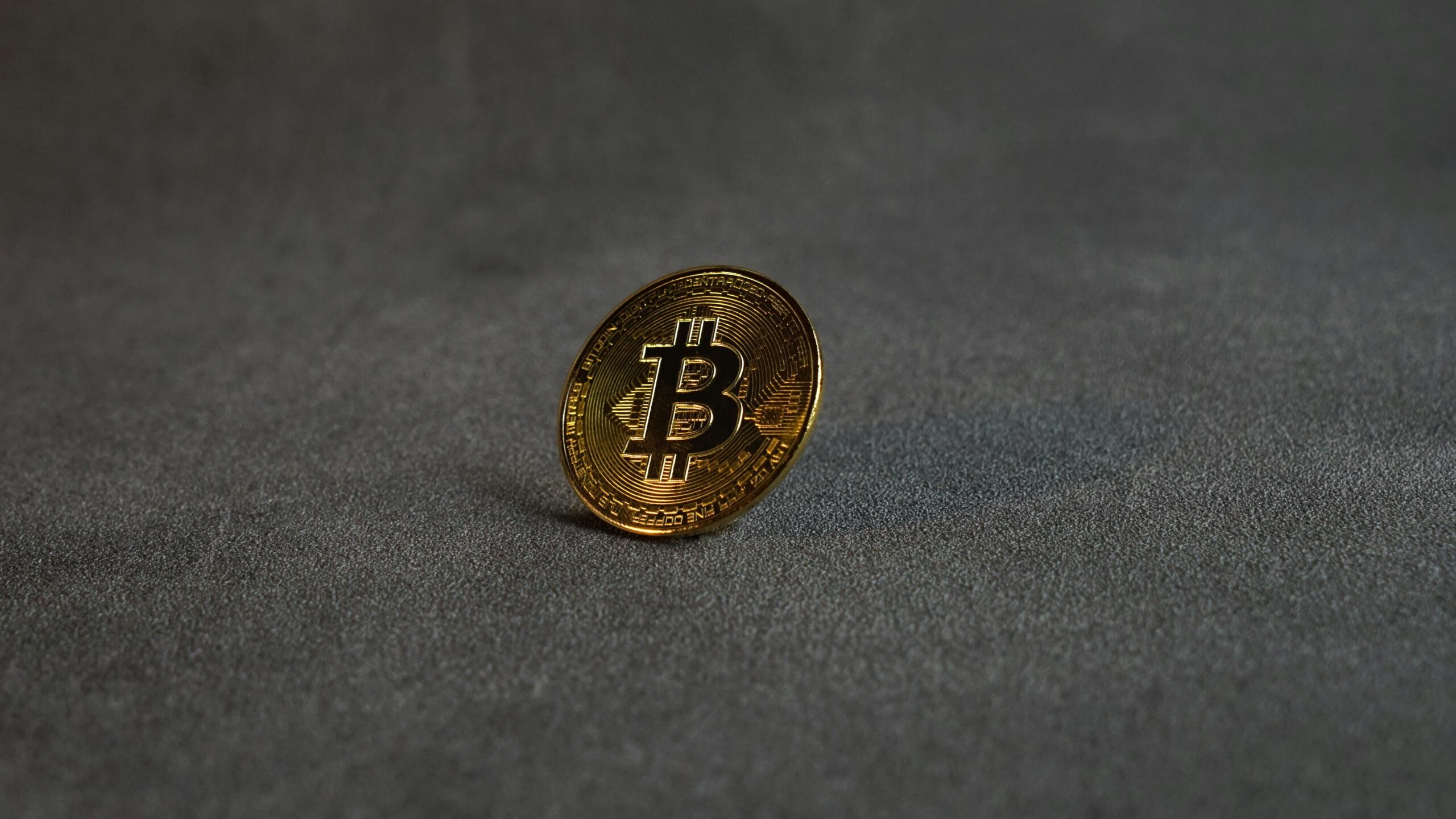 Close-up image of a golden Bitcoin standing on a grey surface, symbolizing cryptocurrency and digital finance.