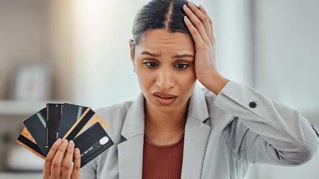Finance debt and credit with a business woman suffering from worry stress and anxiety of inflation in the economy Young female holding bank cards and having problems while trying to pay an account