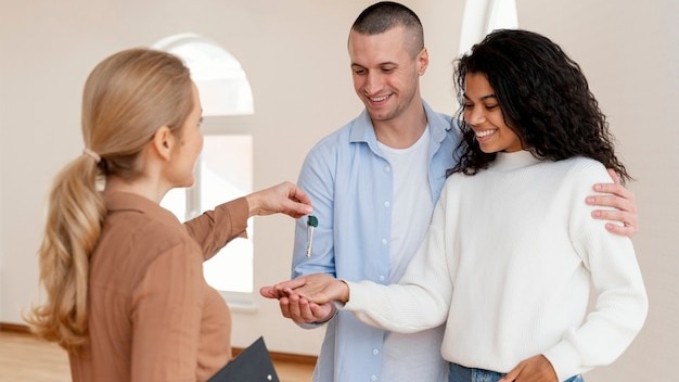 Realtor handing smiley couple the keys for their new home